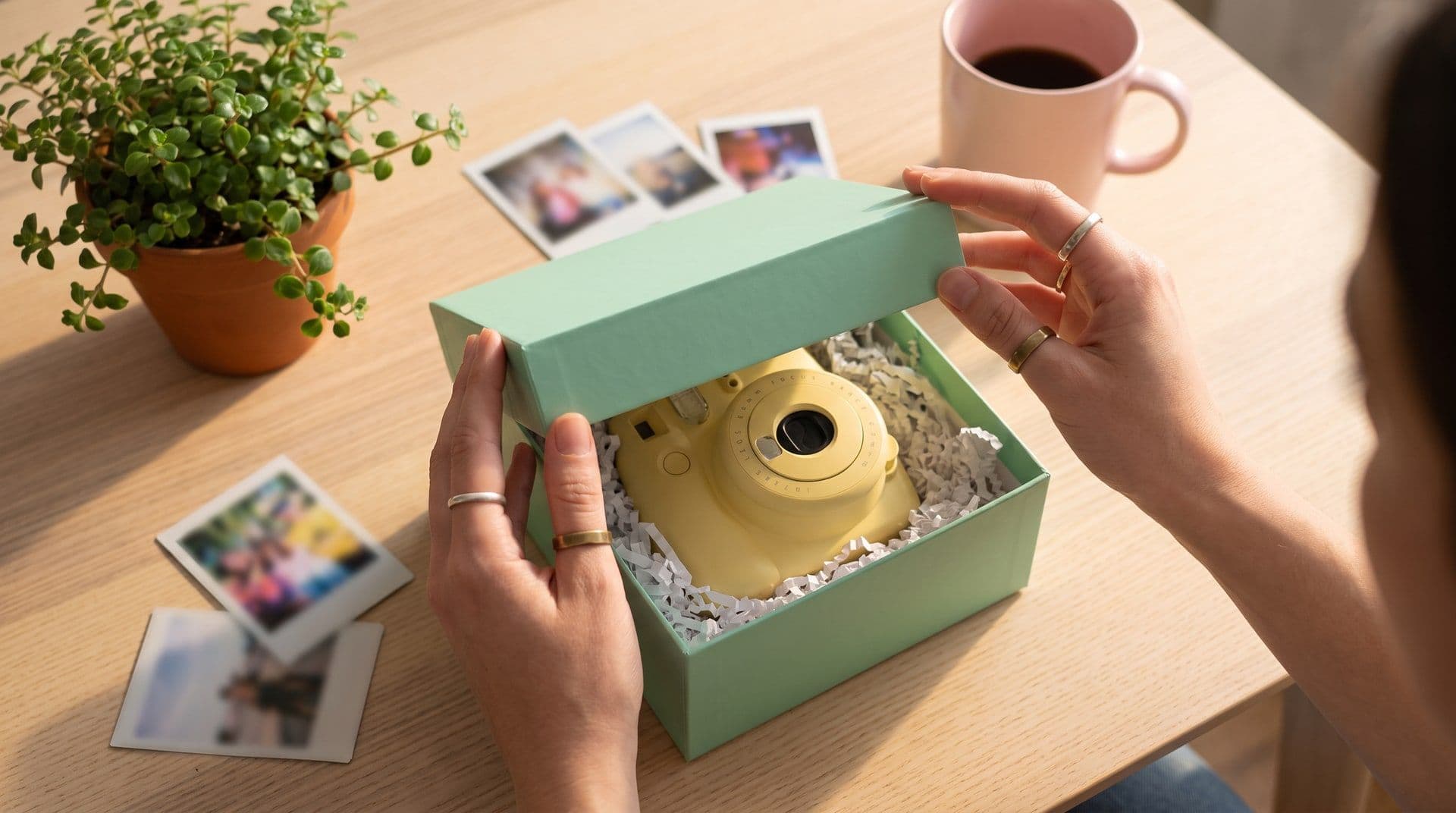 Hands opening a mint-green box with a pastel-yellow instant camera inside. AI-generated · Veo 3.1
