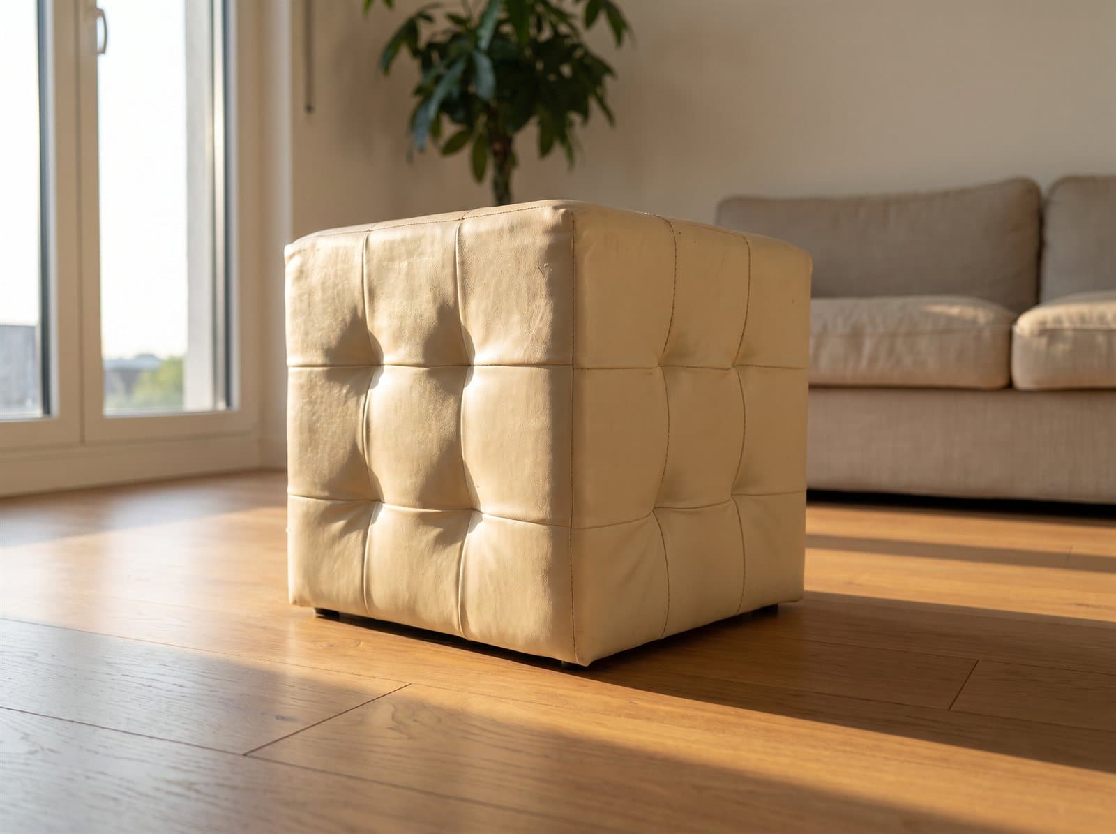 Cream tufted cube pouffe on an oak floor in a sunlit living room. AI-generated · Nano Banana Pro